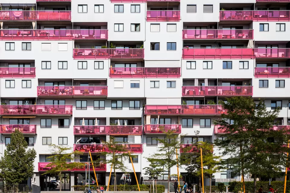 Multistory apartment building facade in Vienna, Austria with pink glass balconies.